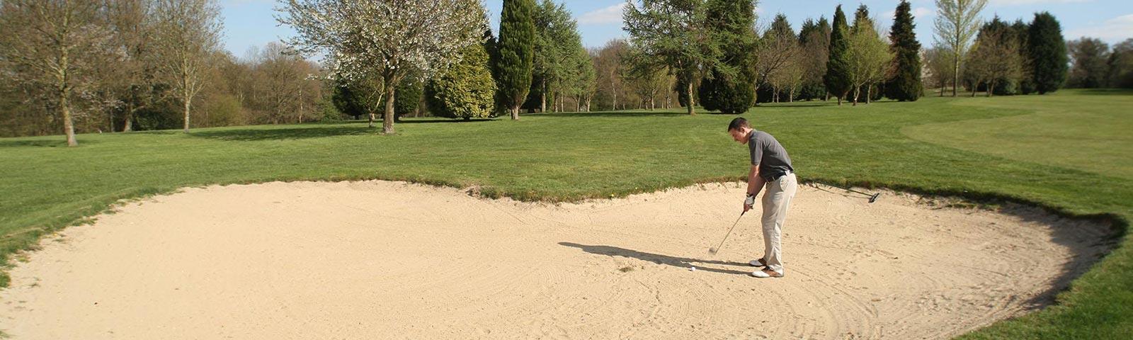 man hitting shot from a sand bunker