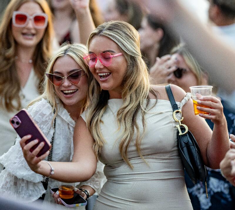 Two ladies at the races smiling and taking a selfie in the crowd at Lingfield races