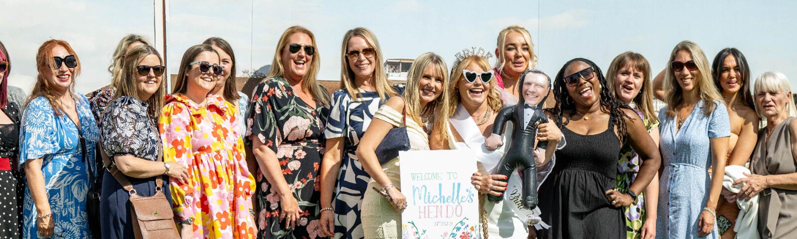 A large hen do posing in front a back drop at Lingfield Races