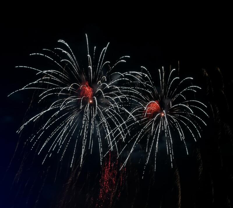 Two fireworks burst in the night sky at a firework display