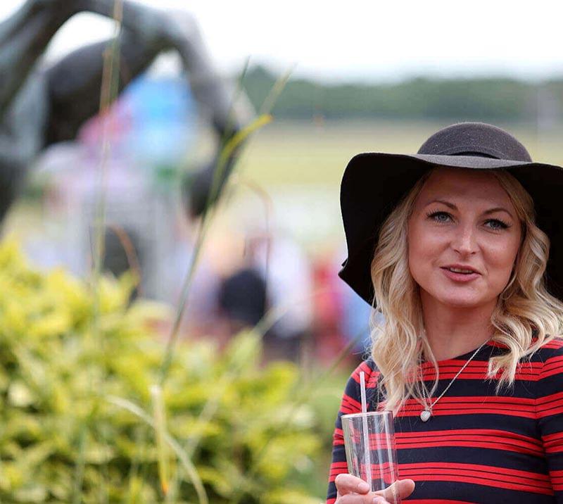 A Lady wearing a black hat and a blac kand red striped jumper.