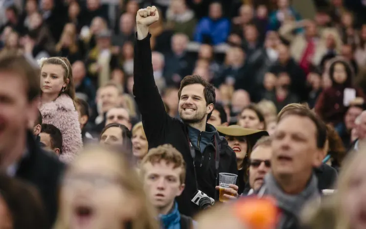 A man in the crowd at Lingfield Races punches the air in celebration