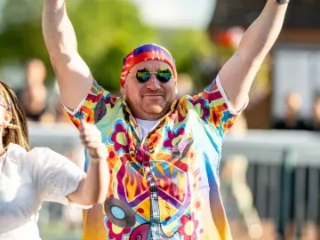 A race goer at Lingfield in fancy dress throws his hands in the air