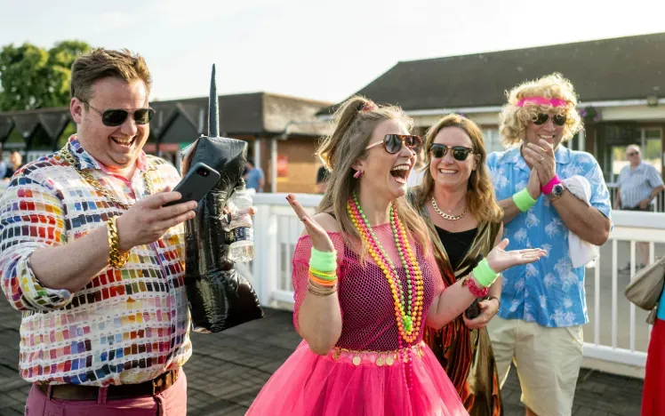 Racegoers at Lingfield dressed for the 80s theme excitedly greet each other