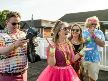 Racegoers at Lingfield dressed for the 80s theme excitedly greet each other