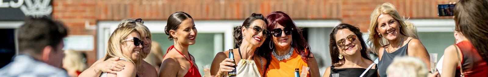 A group of friends all dressed up for the races posing for a picture