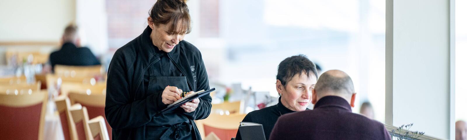 A member of waiting staff for Lingfield Races hospitality taking an order