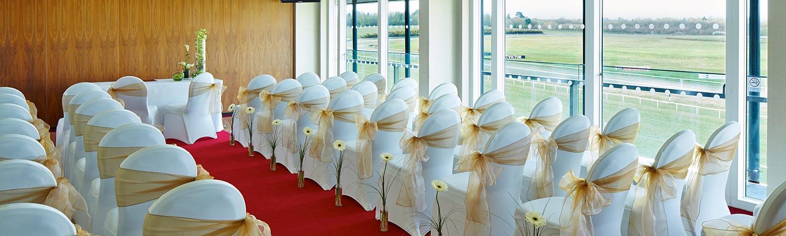 Rows of chairs set up in a room, dressed up for a wedding.