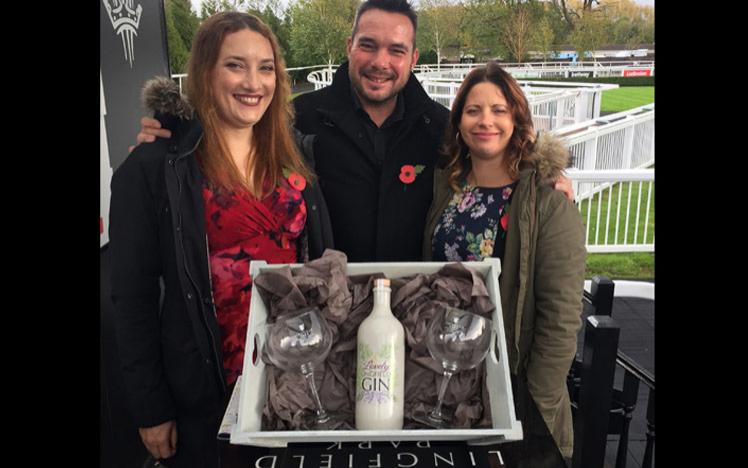 Owners holding a prize box with bottle of gin inside.